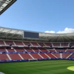 Interior del estadio El Sadar de Pamplona, sede del CA Osasuna, con las gradas rojillas y el césped visto desde la tribuna