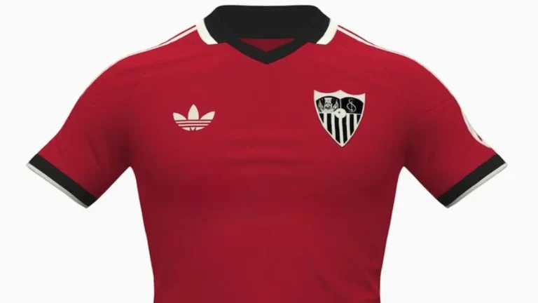 Segunda equipación del Sevilla FC 2026-27 fabricada por Adidas, en color rojo con cuello polo negro, ribetes en beige y logo Trefoil clásico