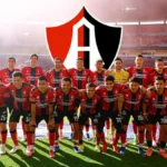 Plantilla del Club Atlas de Guadalajara posando en el estadio Jalisco con el escudo del club rojinegro al fondo