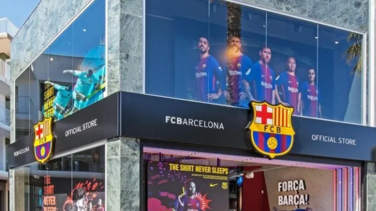 Fachada de la tienda oficial del FC Barcelona con el escudo del club y pantallas de campaña publicitaria
