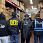 Agentes de ENACOM, DDI y Policía de la Ciudad inspeccionan estantes con cajas de TV Boxes incautados en un almacén durante el operativo antipiratería en Argentina