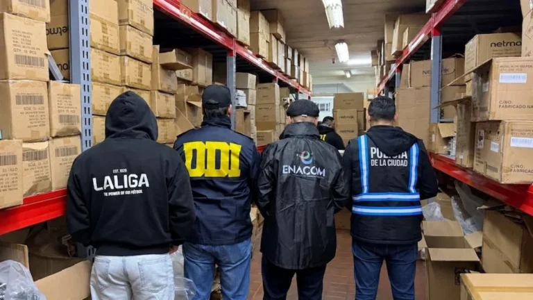 Agentes de ENACOM, DDI y Policía de la Ciudad inspeccionan estantes con cajas de TV Boxes incautados en un almacén durante el operativo antipiratería en Argentina