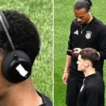 Jamal Musiala con auriculares Beats by Dr. Dre con el logo tapado con cinta adhesiva blanca junto a compañeros de la selección alemana en el terreno de juego