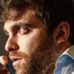 Hombre con traje de camisa blanca habla por teléfono con gesto concentrado, en referencia a la comunicación estratégica en el fútbol