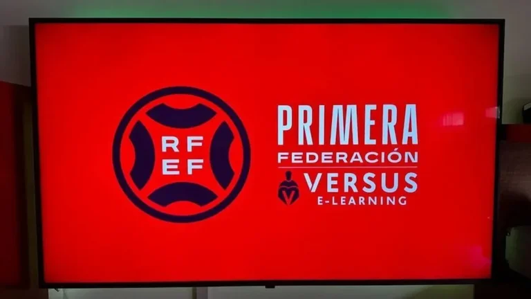Pantalla de TV con el logo de la RFEF y el rótulo Primera Federación Versus e-Learning sobre fondo rojo