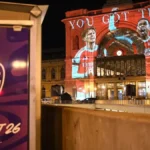 Fachada iluminada de la estación Keleti de Budapest con proyección de dos futbolistas del Arsenal y el logo de la Final de la Champions League Budapest 26
