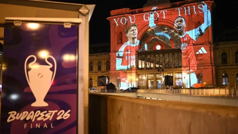 Fachada iluminada de la estación Keleti de Budapest con proyección de dos futbolistas del Arsenal y el logo de la Final de la Champions League Budapest 26