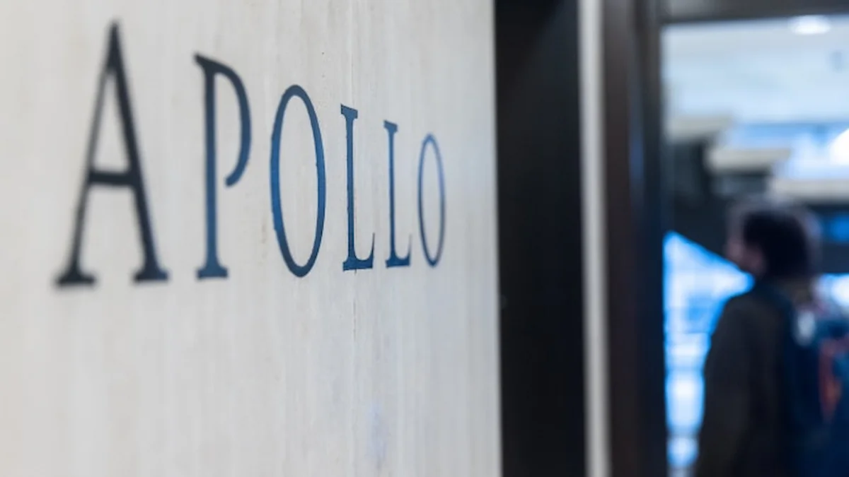 Cartel corporativo con el nombre Apollo grabado en la pared de un vestíbulo, con una persona desenfocada al fondo