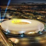 Recreación nocturna del futuro Estadio de Gran Canaria iluminado, con la bahía y la ciudad al fondo