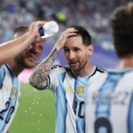 Un compañero moja la cabeza de Leo Messi con agua durante un partido de Argentina