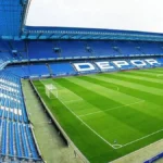 Graderío azul del Riazor con el rótulo Depor sobre el campo vacío antes de un partido