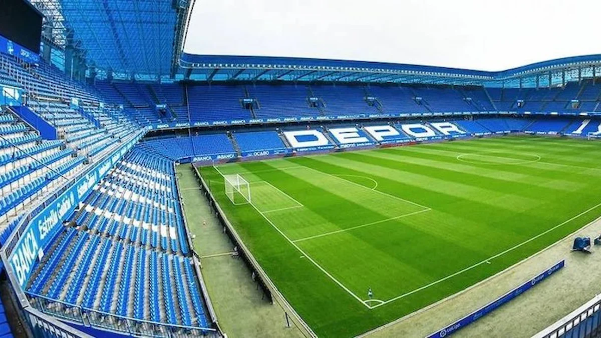 Graderío azul del Riazor con el rótulo Depor sobre el campo vacío antes de un partido