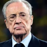 Florentino Pérez, con gesto serio y traje oscuro, junto al césped antes de un partido