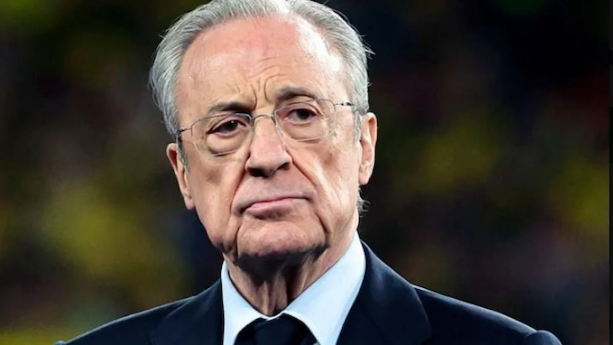 Florentino Pérez, con gesto serio y traje oscuro, junto al césped antes de un partido