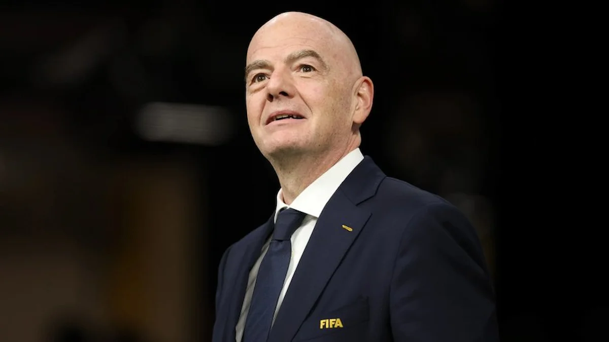 Gianni Infantino, con el pin dorado de la FIFA en la solapa, mirando al frente en un estadio
