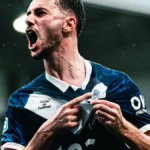 Futbolista con la camiseta del Girondins de Burdeos celebra un gol y señala el escudo bajo la lluvia