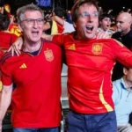 Aficionados con la camiseta de España celebran entre banderas en una fan zone al aire libre