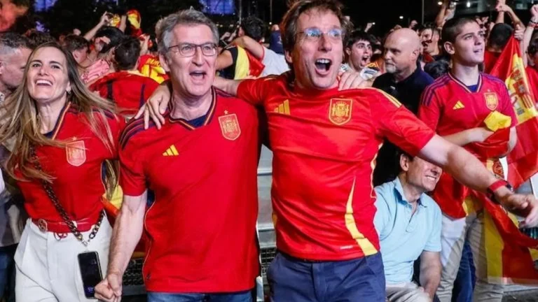 Aficionados con la camiseta de España celebran entre banderas en una fan zone al aire libre