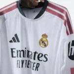 Camiseta blanca del Real Madrid con el logo de Emirates Fly Better en verde sobre el pecho