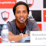 Ronaldinho sonríe en una rueda de prensa sentado ante el micrófono junto al cartel con su nombre