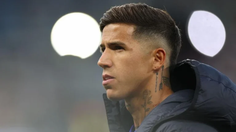 Enzo Fernández con gesto serio en un partido, tatuaje de rosa en el cuello, iluminado por focos de estadio