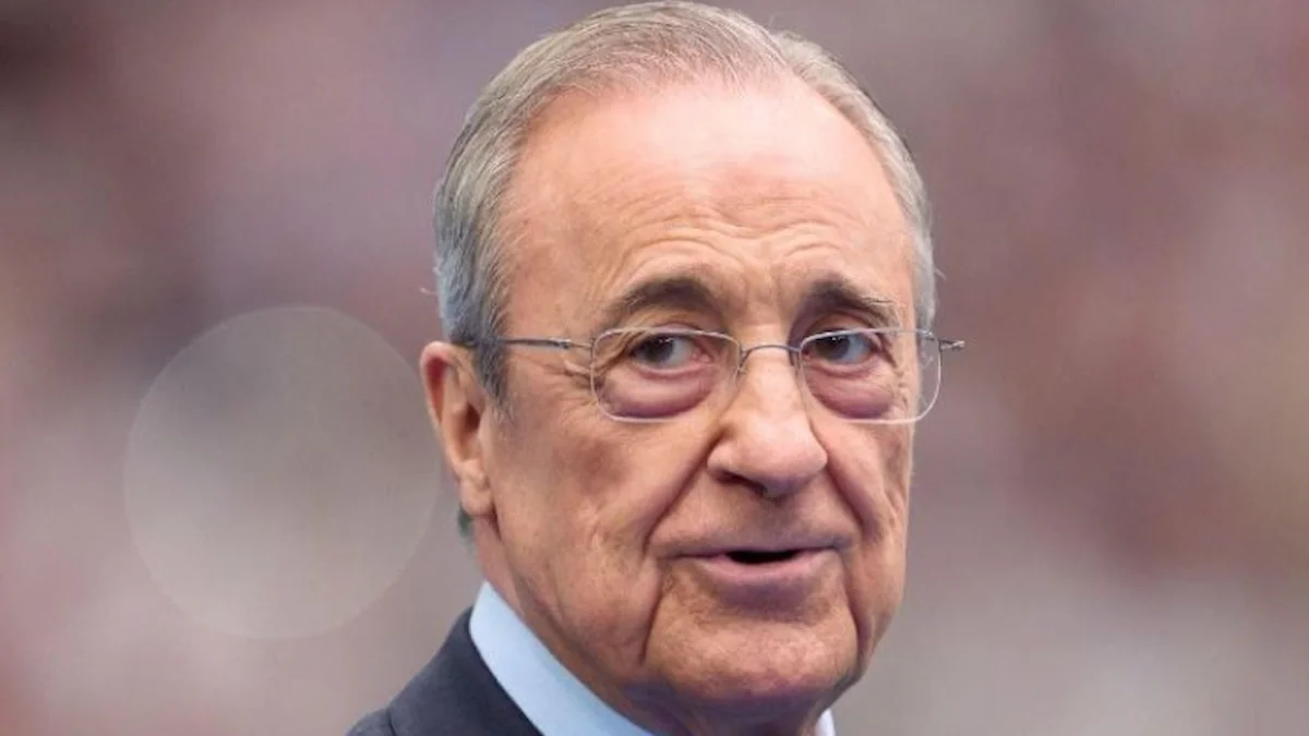 Florentino Pérez, de traje oscuro y gafas, esboza una sonrisa en la grada de un estadio lleno