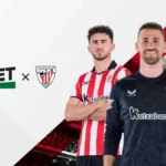 Tres jugadores del Athletic Club con las equipaciones de Castore junto a los logotipos de Linebet y del club sobre fondo blanco y rojo
