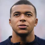 Kylian Mbappé, en primer plano y con gesto serio, antes de un partido con gradas de fondo